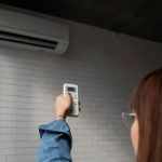 Young woman turning on Air conditioner