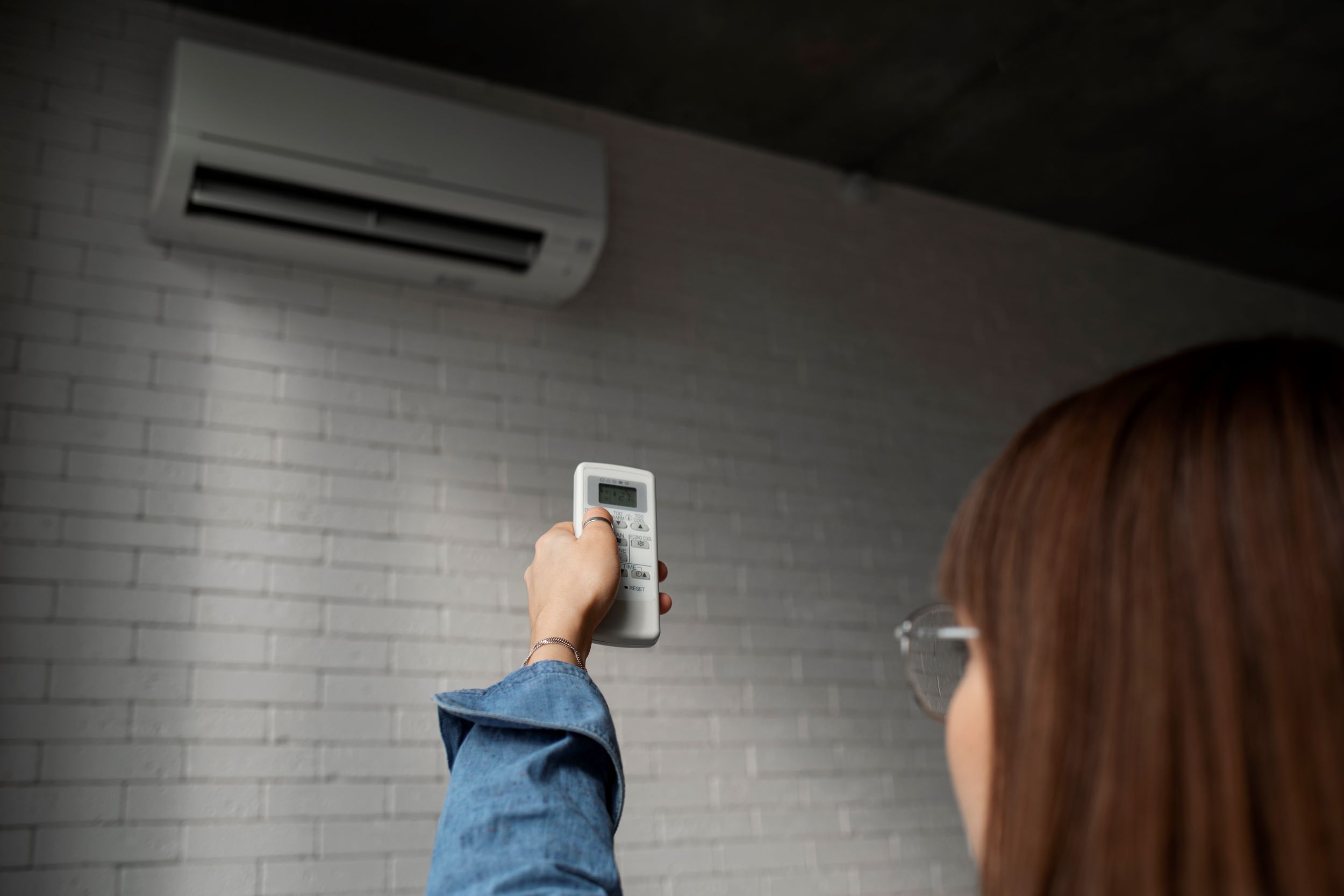 Young woman turning on Air conditioner